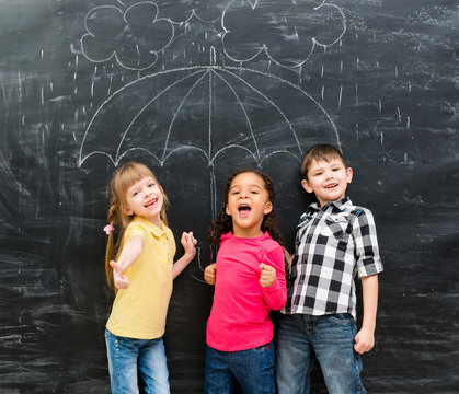 three funny children standing under drawn on blackboard umbrella 