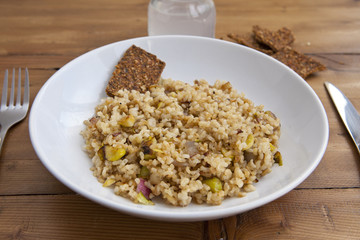 rice with vegetables dish in a wooden background with crackers and lemonade