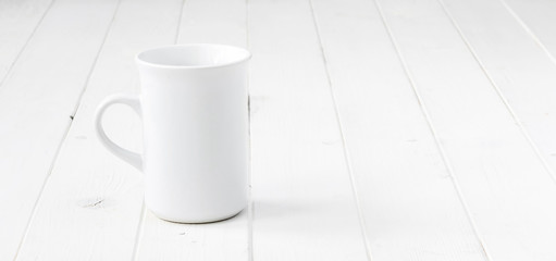 white empty cup on white planked wooden table