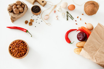 Vegetables, nuts, beans, potatoes, red peppers, chicken eggs, other food and kitchen appliances lie on a white background. Space for text, daylight, horizontal image.