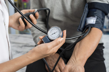 Nurse Holding Gauge While Measuring Blood Pressure Of Patient