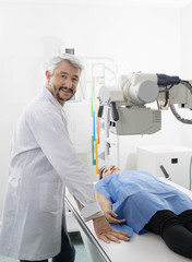Naklejka premium Radiologist Standing By Patient Undergoing X-ray Scan