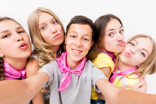 teenage smiling boy making selfie with cute funny girls