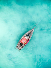 lonely fishing boat in clean turquoise ocean, aerial photo, top view - obrazy, fototapety, plakaty