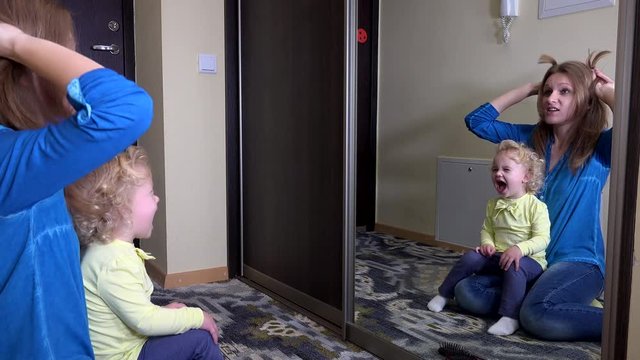 Mother with adorable girl pose in front of mirror