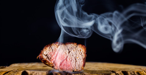 ein saftiges, kurz gebratenes Stück Rindfleisch vor schwarzem Hintergrund