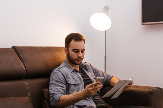 Younger Guy Using His Phone On A Sofa