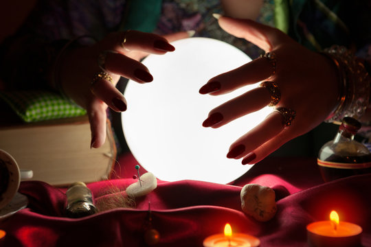 Crystal ball and hands of gypsy fortune teller woman above it