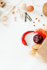 Vegetables, nuts, beans, potatoes, red peppers, chicken eggs, other food and kitchen appliances lie on a white background. Space for text, daylight, horizontal image.