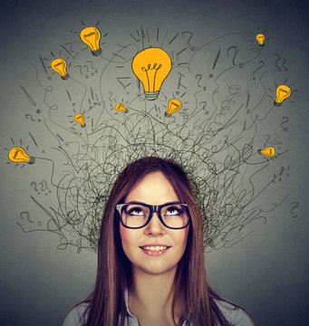 Woman in glasses with many ideas light bulbs above head looking up