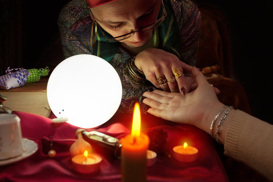 Fortune teller woman holding another woman hand for palm reading