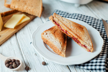 Hearty and traditional breakfast, sandwiches with rye toast, sausage, cheese, spices and black tea on a light wooden background