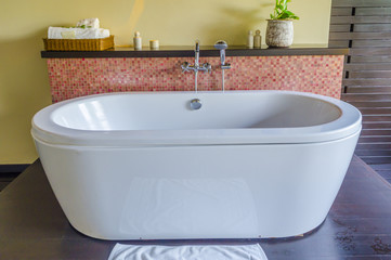free standing contemporary ceramic bath tub and stone tile wall