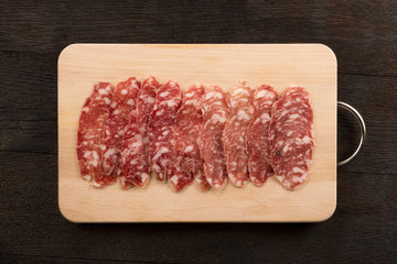 Italian salami sliced on wooden cutting board