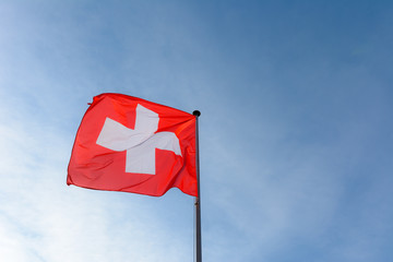 Schweizer Flagge an Fahnenstange vor blauem Himmel