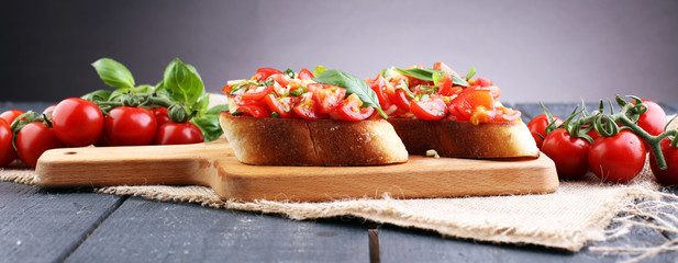 Tasty savory tomato Italian appetizers, or bruschetta, on slices of toasted baguette garnished with...