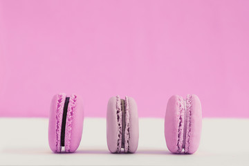 Obraz premium Assorted pink and purple french macaroons on a colored background. Copy space for text. Horizontal