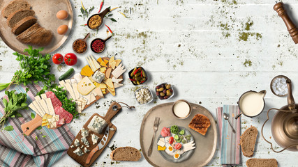 Overhead view of colorful roast vegetables, savory sauces and salt served with grilled t-bone steak on a rustic wooden counter in a country steakhouse