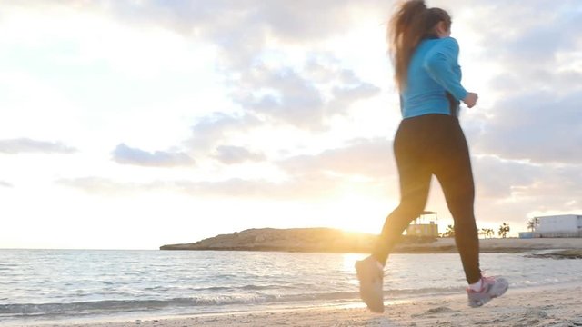 Woman running on the beach at sunset