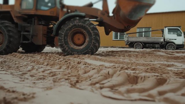 loader excavator machine loading dumper truck at sand quarry, new factory building