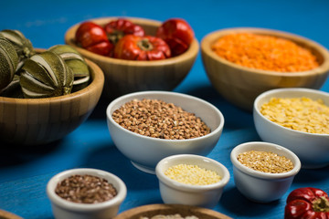Bowls and spoons of various legumes on wooden table