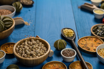Bowls and spoons of various legumes on wooden table