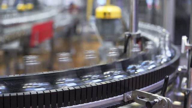 Spill in glass bottles at the plant. Conveyor belt with glass bottles. transporter close-up. The production process of alcoholic beverages.
