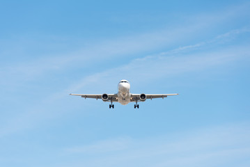 Commercial airplane flying in blue sky, full flap and landing gear extended