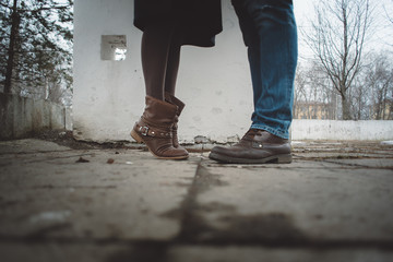 legs of a young girl with brown boots and a man in blue jeans and boots in the spring on the street...