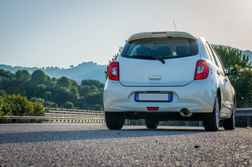 Fototapeta na wymiar Small white car with led optics on the asphalt road highway 