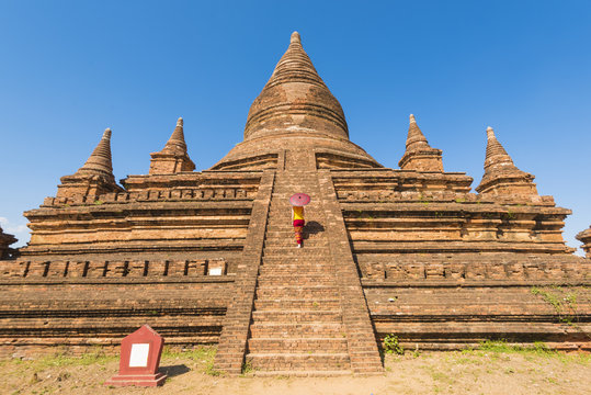 Bagan, Mandalay region, Myanmar (Burma). Woman walking on the steps of a stupa. MR.