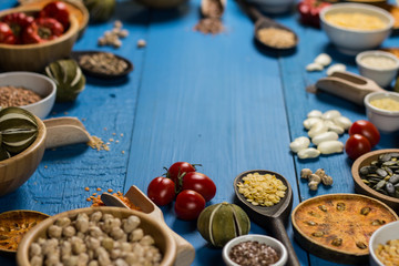 Bowls and spoons of various legumes on wooden table