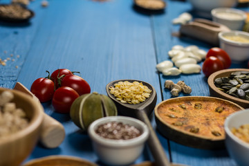 Bowls and spoons of various legumes on wooden table