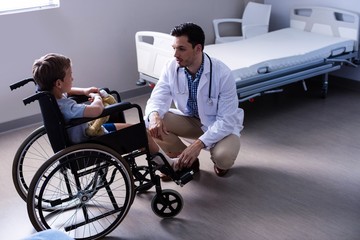 Male doctor interacting with child patient in ward