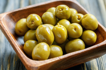 Green olives in a bowl close-up.