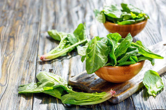 Wooden bowls with spinach leaves.