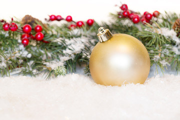 Fototapeta na wymiar Gold Christmas Ornament With Greenery and Snow