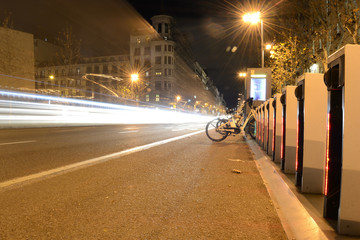 Rays of traffic lights, next to a bicycle parking in a street, by night