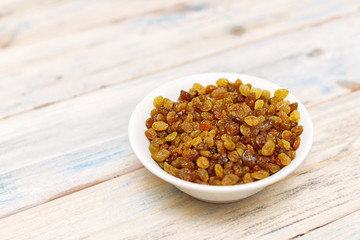 Raisins in a bowl on a wooden background