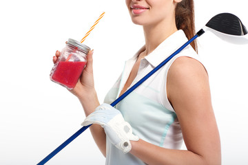 Pretty girl golfer posing with with jar of detox juice on white backgroud in studio