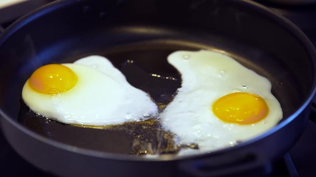 Fried eggs on a black frying pan closeup
