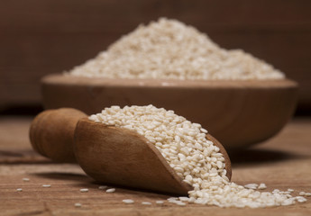 Fresh sesame seeds in a wooden bowl and spoon