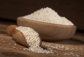 Fresh sesame seeds in a wooden bowl and spoon