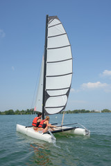 young couple steering a catamaran
