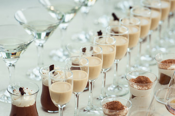 Beautiful row line of different colored alcohol cocktails on a party, Whisky cognac, liquor.