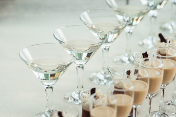 Beautiful row line of different colored alcohol cocktails on a party, Whisky cognac, liquor.