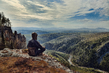 Man hiker sitting on top of mountain in rainy day, it is wet bad weather.