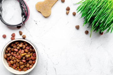 dry dog food in bowl on stone background top view