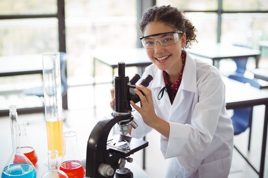 Portrait of schoolgirl experimenting on microscope in laboratory