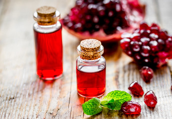 sliced pomegranate and extract in glass on wooden background